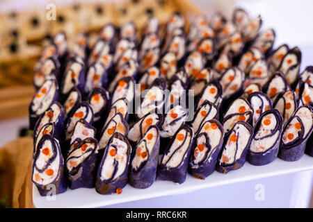 Rollen schwarz Pfannkuchen mit Käse, Lachs und roter Kaviar auf die weiße Platte, schöne Präsentation. Stockfoto