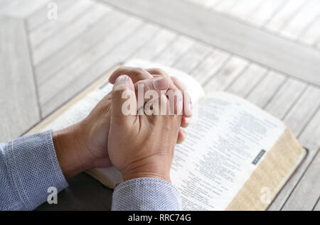 Beten: männlich gefalteten Händen zusammen auf eine alte Bibel Stockfoto