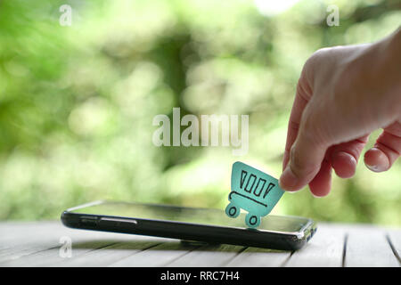 Online einkaufen oder ecommerce Konzept: ein Papier Warenkorb oben auf einem Smartphone Stockfoto