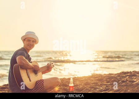 Junger Mann Gitarre spielen am Strand Stockfoto
