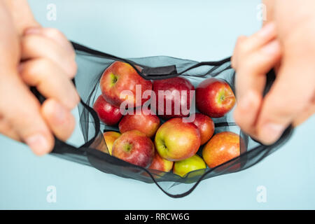 Holding eine wiederverwendbare string Beutel voller Äpfel. Nachhaltige ökologische Verpackungskonzept: Einkaufsmöglichkeiten für Lebensmittel mit einem Multi-bag ökologische Fuß zu verringern Stockfoto