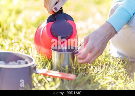 Mädchen gießt Wasser aus dem Wasserkocher Stockfoto