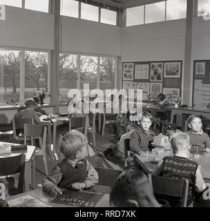 1950er Jahre, junge Kinder sitzen gemeinsam am Schreibtisch in einem hellen, Licht, Babysitting-Service, spielen mit Holz- Ziegel, Zeichnen und Schreiben mit Kreide. Stockfoto