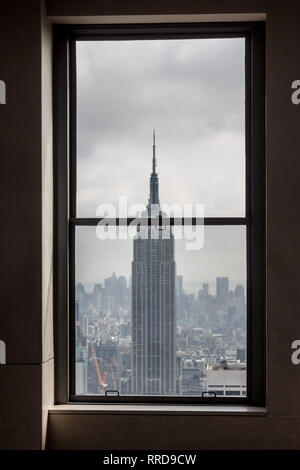 Blick aus dem Fenster auf das Empire State Building in New York und bewölkter Himmel Stockfoto