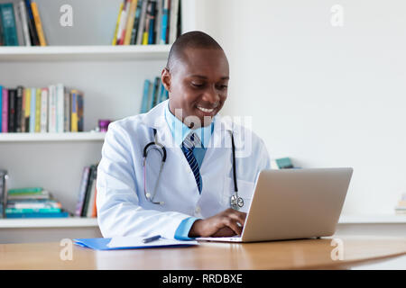 Afrikanische amerikanische Arzt für Allgemeinmedizin, am Computer im Krankenhaus zu arbeiten Stockfoto