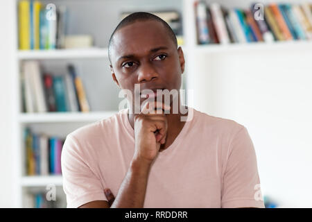 Denken afrikanische amerikanische Mann mit Glatze drinnen zu Hause Stockfoto