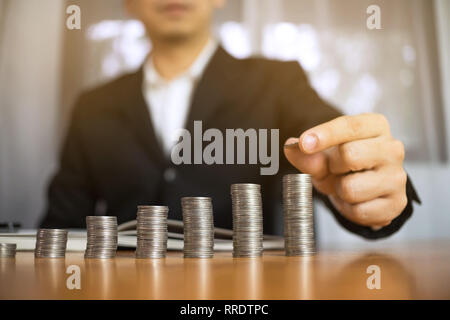 Geschäftsmann nimmt Münzen auf den Tisch und zählt Geld. Geschäftskonzept. Stockfoto