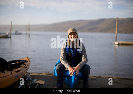 Porträt eines lächelnden Mitte - erwachsene Frau sitzt auf einem Bootsanleger. Stockfoto