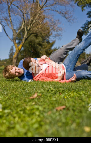 Lachend Teenager paar Spaß playfighting auf einem Rasen. Stockfoto