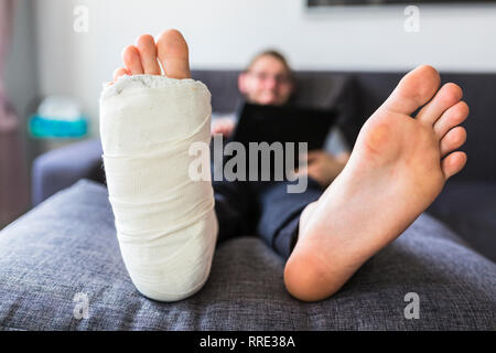 Mann zu Hause sitzen mit gebrochenen Bein Stockfoto