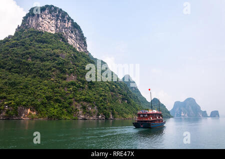 Einen hölzernen Dschunke Boot segelt vorbei am großen Kalkstein Karst Insel in Ha Long Bay, Vietnam Stockfoto