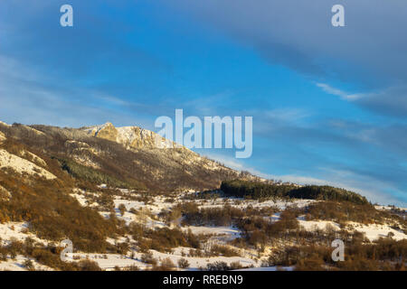 Fernen schneebedeckten felsigen Gipfel und bunten Wald im Winter Wunderland unter blauen Himmel Stockfoto