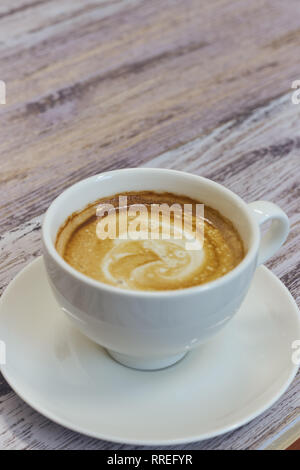 Weiße Tasse Kaffee auf einem Holztisch. schwarzer Kaffee mit Milch. Holztisch mit einem duftenden Stockfoto
