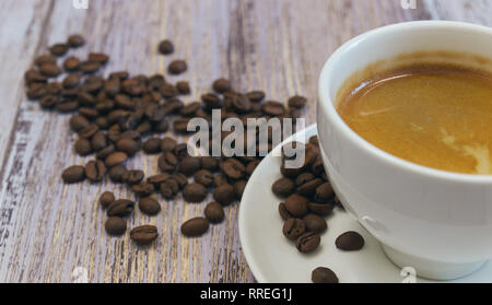 Eine Tasse duftenden schwarzen Kaffee und eine Handvoll Kaffeebohnen auf einem alten Holztisch close-up. Am Morgen zu trinken. Stockfoto