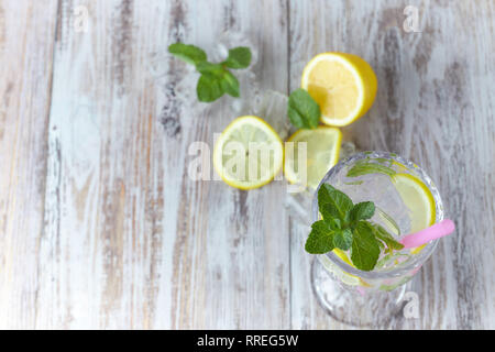 Wasser mit Zitrone und Minze im Glas Container auf einem Holztisch. Platz für Text. Erfrischende Sommer Zitrusfrüchten trinken. vertikale Ansicht des Sommers Stockfoto