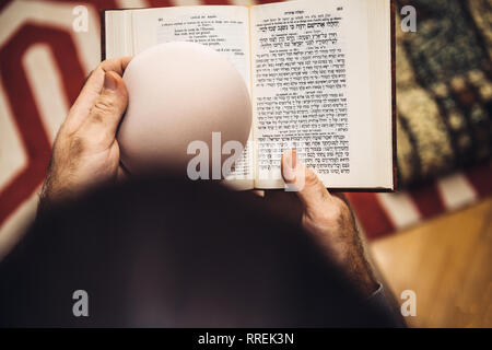 Blick von oben der Jüdischen männlichen Holding Kippa betende Lesung Mehrsprachig Hebräisch Französisch machzor Gebetbuch von 1920 auf die Hohen Feiertage Rosch Haschanah und Jom Kippur verwendet Stockfoto