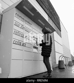 Straßburg, Frankreich - Feb 8 2018: Junge Frau mit Amazon Spind die Self-service-Paketdienst Station in der Nähe von Auchan Supermarkt mit Touchscreen Display code eingeben Karton abzurufen - Schwarz und Weiß Stockfoto