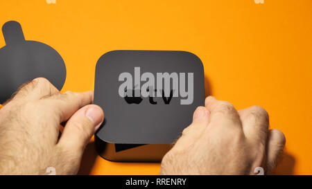 Paris, Frankreich, 24.Oktober 2018: die männlichen Händen unboxing Apple TV gegen orange Hintergrund - TV-Streaming mit Apple Logo an der Oberseite Stockfoto