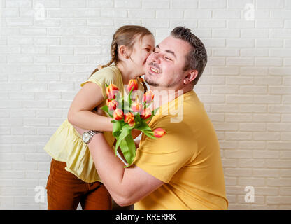 Tochter ihrem Vater am Vatertag zu küssen. Glückliche Familie Tochter und Papa Blumen Stockfoto