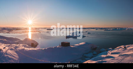 Leuchtend rosa Sonnenuntergang über der Antarktis Shoreline und wernadsky Station. Herrlicher Panoramablick der Sonnenbeschienenen polar Bay. Die schneebedeckten Oberfläche der Südpol neben dem gefrorenen Wasser Oberfläche. Stockfoto