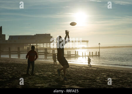 Zwei Jungen spielen mit einem amerikanischen Fußball auf Aberystwyth Beach in Wales, da wurde ein neuer Rekord für den wärmsten Februar Tag der britischen eingestellt. Das Thermometer erreicht 20,3 C (68,5 F) bei Trawsgoed in Ceredigion, West Wales und schlug den bisherigen Rekord von 19,7 C (67,4 W) in Greenwich 1998 aufgezeichnet. Stockfoto