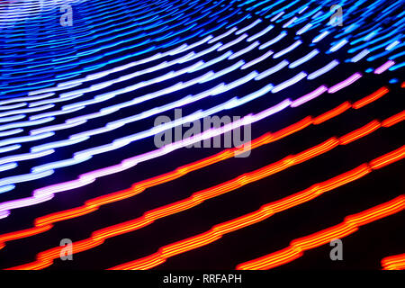 Bunt leuchtende Linien in Bewegung auf dem dunklen Hintergrund. Sie sind rot, violett, orange und blau. Closeup horizontale Foto. Stockfoto