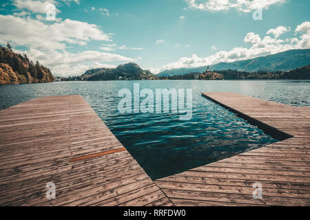 Hölzerne Pier am Bleder See in Slowenien mit der berühmten Insel und Schloss im Hintergrund Stockfoto