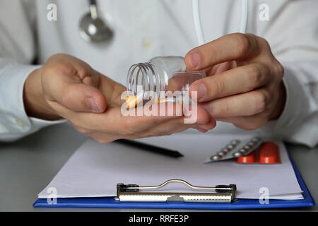 Arzt mit Pillen am Tisch sitzen, die Medikation in Kapseln. Konzept der medizinischen Untersuchung im Amt, die Dosis der Medikamente, ärztliche Verschreibung Stockfoto