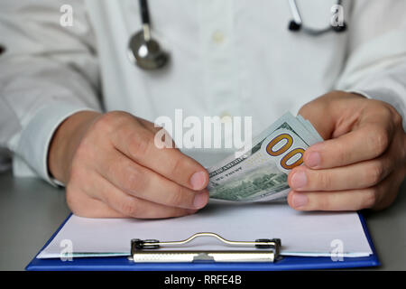 Arzt sitzen am Tisch mit Dollar in den Umschlag. Konzept für die Annahme von Bestechungsgeldern, Geld für medizinische Untersuchung, Bestechung, Korruption oder teure Healthcare Stockfoto