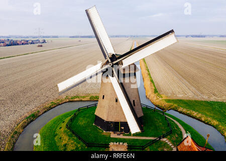 Typische holländische Windmühle aus dem 17. Jahrhundert Schuß von oben mit einer Drohne durch einen Kanal in den Bereichen Holland umgeben Stockfoto