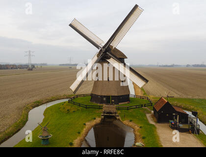 Typische holländische Windmühle aus dem 17. Jahrhundert Schuß von oben mit einer Drohne durch einen Kanal in den Bereichen Holland umgeben Stockfoto