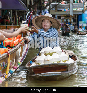 Damnoen Saduak, Thailand - 29. August 2018: Frau verkauft Kokosnüsse von einem Boot in Damnoen Saduak Markt, Ratchaburi, Thailand. Stockfoto