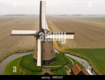 Typische holländische Windmühle aus dem 17. Jahrhundert Schuß von oben mit einer Drohne durch einen Kanal in den Bereichen Holland umgeben Stockfoto