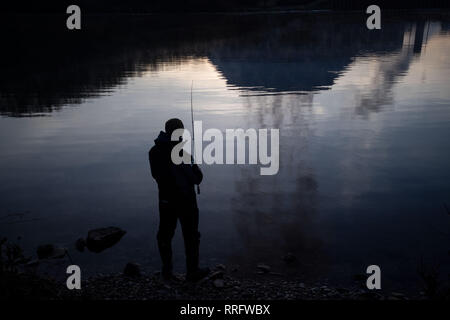 Neckarwestheim, Deutschland. 26 Feb, 2019. Ein Mann angeln am Neckar, der Kühlturm des Kernkraftwerks Neckarwestheim spiegelt sich im Wasser. Credit: Marijan Murat/dpa/Alamy leben Nachrichten Stockfoto