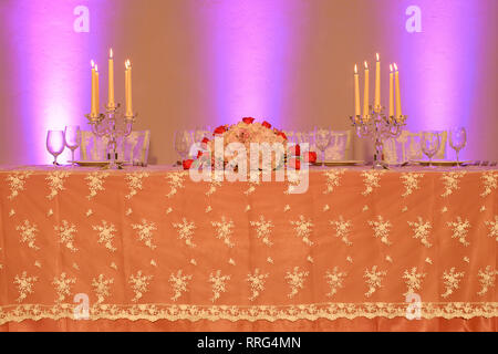 Hochzeit oder Fine Dining Table Setup mit besticktem organza Tischdecke, kristall Kerzenhalter und ein Blumenarrangement Mittelstück Stockfoto