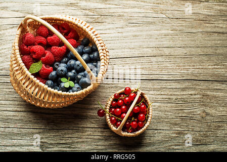 Mix aus frischen Beeren Obst in einem Korb auf Holz- Hintergrund Stockfoto