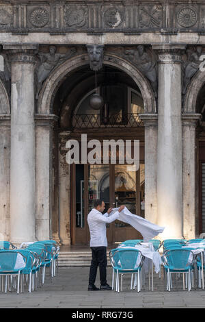 Ein Kellner bereitet Tabellen in einem Cafe in der Markusplatz in Venedig. Aus einer Reihe von Fotos in Italien. Foto Datum: Dienstag, 12. Februar 2019. Pho Stockfoto