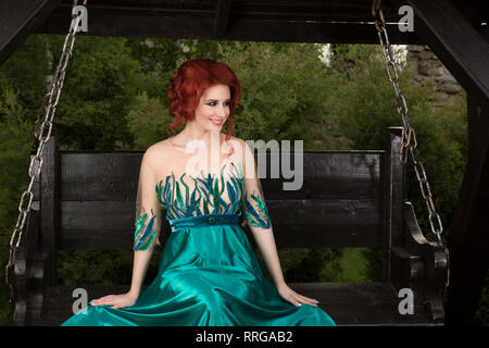Schöne Lesekopf Frau in einem Cocktail Kleid ist in einem Stuhl sitzend, entspannen, in Ruhe, lächelnd, glücklich auf der Seite glücklich. positive Gesicht ex Stockfoto