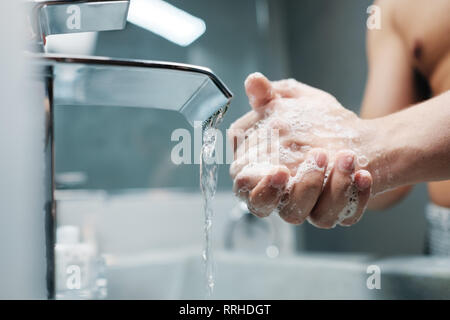 Man Waschen der Hände mit Wasser und Seife im Bad Stockfoto