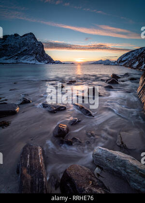 Sonnenuntergang vom Strand auf der Halbinsel Kjerringøy in Nord Norwegen mit der Bewegung der Wellen im Vordergrund gesehen. Stockfoto