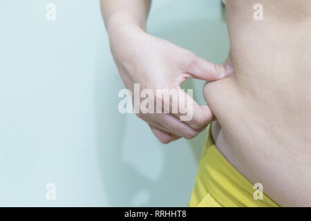 Woman's Hand hält eine Falte der überschüssiges Fett auf ihrem Bauch, Bild mit kopieren. Stockfoto