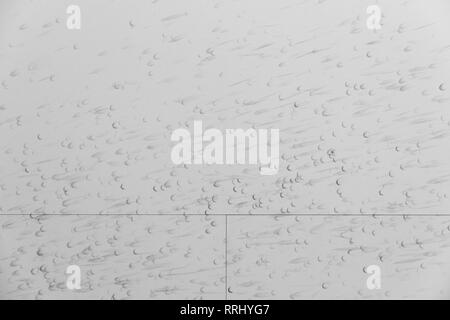 Detail of a white wall with many black traces left by a squash ball. Red floor. Photographed on a public outdoor sports ground Stockfoto