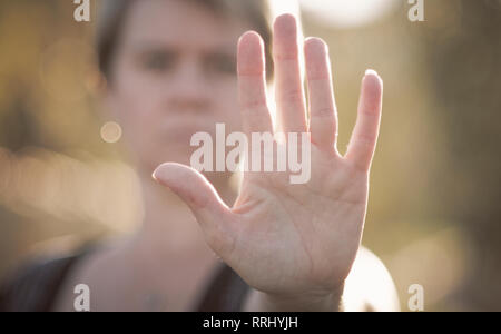 Hält eine Frau ihre hatte zu zeigen top' oder 'Frieden und aufhören" an einem Sommertag. Stockfoto