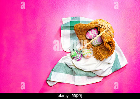 Bunte Ostereier aus Stoff auf Holz- korb mit Serviette und rosa Farbe Hintergrund verschüttet. Frohe Ostern Stockfoto