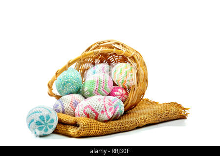 Bunte Ostereier aus Holz- korb mit Stoff auf weißem Hintergrund verschüttet. Frohe Ostern Stockfoto