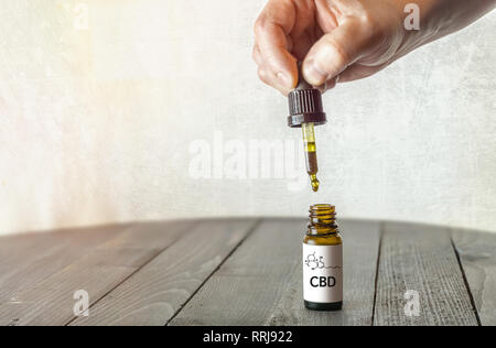 Hand, die Pipette mit CBD Öl auf Holz- Tisch mit Platz kopieren Stockfoto