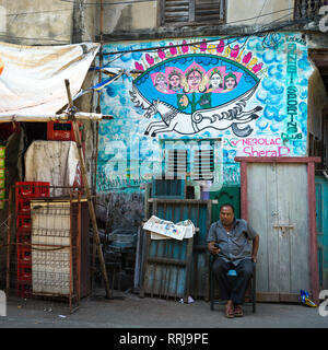 Mann sitzt im vorderen Ladenbereich, Abhedananda Straße, Kolkata, West Bengal, Indien Stockfoto