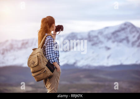 Schöne Frau mit Rucksack ist unter Foto von Berg Stockfoto