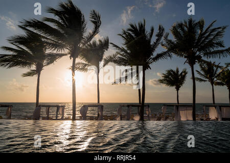 Lounge Bereich eines High End mexikanisches Resort mit einem Infinity-Pool mit Blick auf das Meer bei Sonnenaufgang. Stockfoto