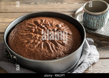 Frisch gebackenes köstlich duftende Schokolade Kuchen kühlt in kulinarischer Form auf einem Holztisch Stockfoto